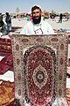 Pashtun vendor displaying a silk rug from Afghanistan