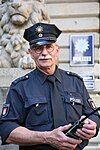 A middle aged man in blue uniform in with a radio device.