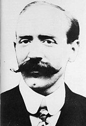 portrait photo of a balding man with a large moustache