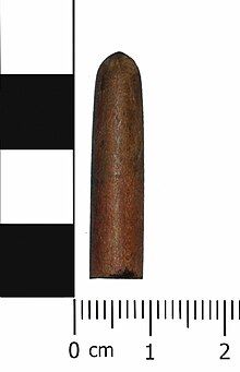 A wooden bullet shaped object. It is smooth all over and brown in colour. probably used for practice firing. Rather than simply firing blank cartridges, some automatic weapons, particularly machine guns required a projectile in order to produce the n