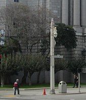 A square utility pole with an ornamental streetlight