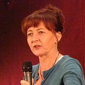 A 48-year-old woman with brown hair, talking to someone to the left of the camera.