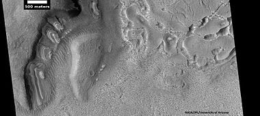 Dipping layers, as seen by HiRISE under HiWish program. Also, Ribbed Upper plains material is visible in the upper right of the picture. It is forming from the upper plains unit, and in turn is being eroded into brain terrain.