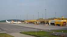 A mostly yellow airport terminal seen from the apron; furthest away there are two jet planes parked