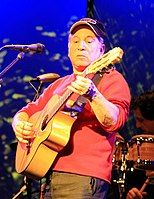 A man playing guitar on stage with a band