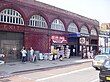 A red-bricked building with a sign reading "EXIT HOLLOWAY ROAD" in gold letters and a rectangular, blue sign reading "HOLLOWAY ROAD STATION"