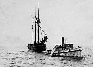 A small schooner under tow by a small steamship