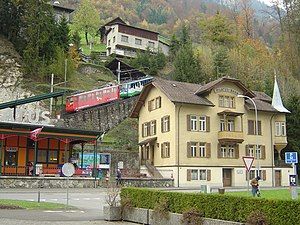 Train ascends incline behind four-story building with gambel roof