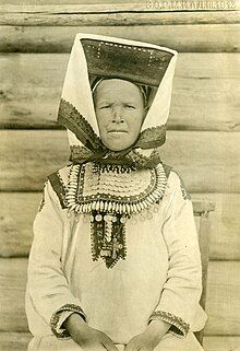 Monochromatic photo portrait of a woman wearing elaborate traditional clothing including an ornate headdress.