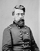 Black and white photo shows a bearded man with light-colored eyes. He wears a dark military uniform with two rows of buttons and the shoulder tabs of a major general (two stars).