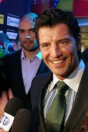 Smiling man in a suit, talking into two microphones