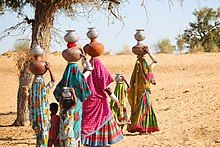 Women and children carrying pots filled with water in Thar desert