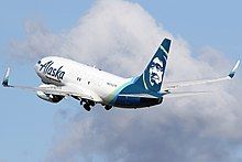 A plane painted with the words "Alaska Air Cargo" across it takes off