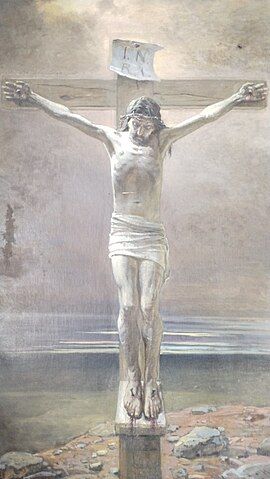 Crucified Jesus on a large wooden cross against the backdrop of a seashore, sea, and sky. A plaque above Christ's head says "INRI".