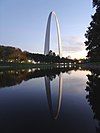 huge arching parabolic structure, reflected in the water, at dusk