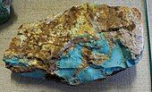 An uncut nodule of brown matrix with a split face showing areas of turquoise.