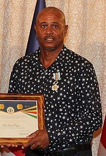 Cadeau-Payet facing the camera, holding a certificate and with a medal pinned onto his shirt.