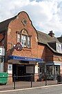 A brown-bricked building with a rectangular, dark blue sign reading "WEST HAMPSTEAD STATION" in white letters all under a blue sky