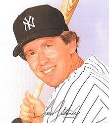 A man in a white jersey and navy cap