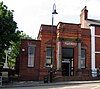 A brick building with a protruding entrance bay flanked by stone columns