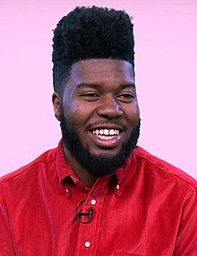 Khalid smiling while wearing a red shirt