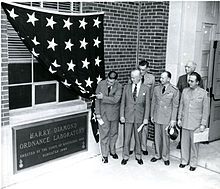 Army officials unveil a large plaque on a building that reads “Harry Diamond Ordnance Laboratory” with the text “Erected by the Corps of Engineers 1945 Dedicated 1949” underneath.