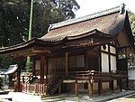 Wooden building with an asymmetric gabled roof and a raised veranda with handrail.