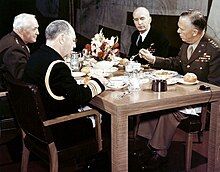 Color photograph of four uniformed men seated at a lunch table