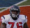 An African-American male wearing a football uniform and helmet. The uniform is blue, red, and white