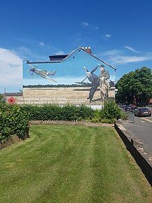 A mural on the side of a house in the town of Loughborough, UK, depicting Johnson. The house is across the road from Loughborough Grammar School, where Johnson was educated. The Mural is based upon a photograph of Johnson taken at Bazenville Landing Ground, Normandy, July 1944, with his Labrador, Sally.