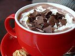 A cup of hot chocolate with whipped cream and chocolate shavings.