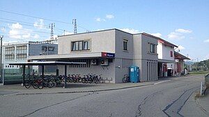 Boxy two-story structure with canopy-covered bike racks in front