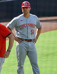 A man in a gray baseball uniform and red batting helmet