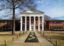 A brick building with white ionic columns in the center