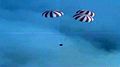 Screenshot of video by NASA chase-plane of Dragon C2+ with its 3 main parachutes deployed.