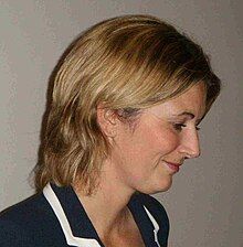 Headshot of a blonde-haired woman in a blue blouse.