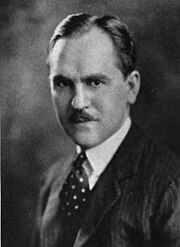 A black and white portrait of a mustachioed Francis Keally in a suit and tie