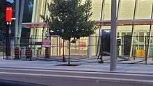 Photo of a modern, glass-panelled light rail station entrance under construction which appears largely complete