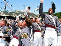 Several West Point cadets tossing their hats in the air at graduation