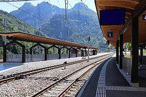 Train platforms with a wooden shelter and a white and red train