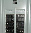 Illustration of breaker numbering in a North American type panelboard. Some labels are missing, and some are additional. The numbers on the toggles indicate the rated amperage before tripping. The top right breaker (Rated at 100 A) feeds a sub panel.