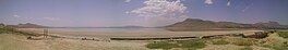 A panoramic view of a desert landscape with a body of water in the distance.