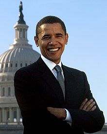 Photo of Obama smiling with his arms crossed, with the Capitol building and the sky in the background