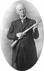 John Moses Browning holding a Browning semi-auto .22 rimfire rifle