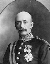 Upper body of a bald man with a large moustache. He is in a military uniform with several medals pinned to his left chest.