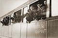 A group of Jewish child Holocaust survivors lean out of a train carriage bearing the graffiti Hitler kapout as it departs Buchenwald, June 1945