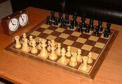 Staunton chess pieces on chess board with chess clock