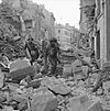 Troops of I Corps pick their way through the rubble of Caen