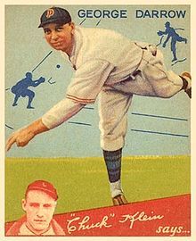 A man in a white baseball uniform and navy blue cap