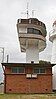 A concrete square tower supporting a semicircular structure resembling an airport control tower